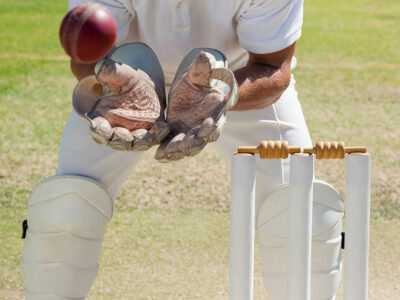 Mid section of wicketkeeper catching ball behind stumps 